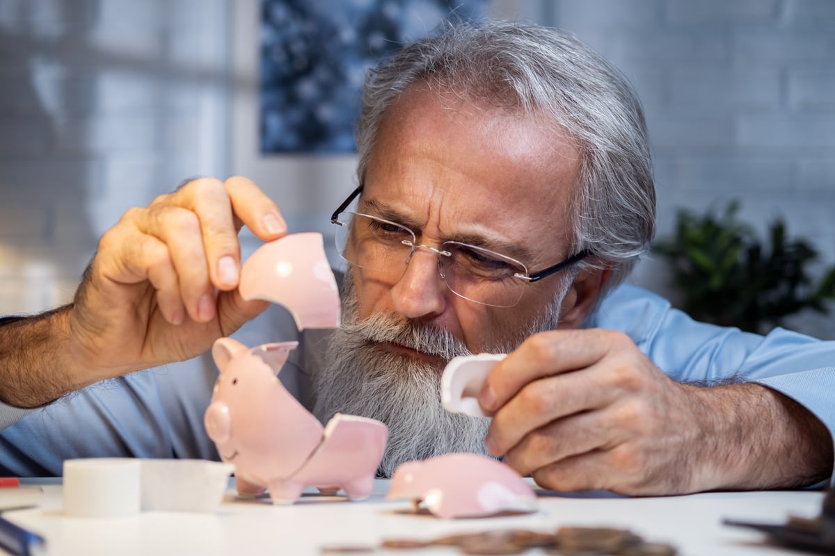 23_11_02 A person examining the pieces of a broken piggy bank _MF Dload GettyImages-1410584108