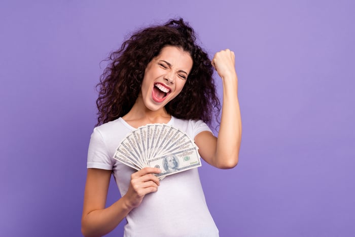 A person holding a stack of money and celebrating.