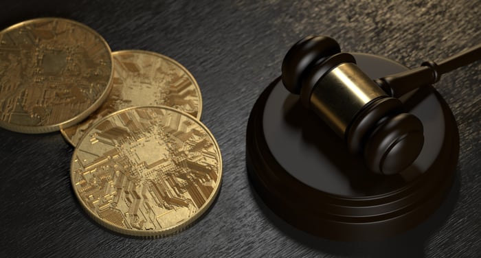 A judge's gavel and several golden coins.