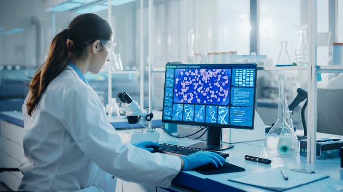 Medical technician looks at computer screen in lab. 
