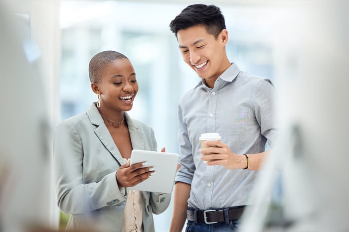 Two people looking at tablet and smiling.
