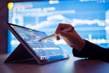 A person using a pen to point at a stock chart on a tablet.