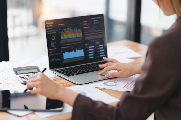 A person looks at charts and data on a laptop.