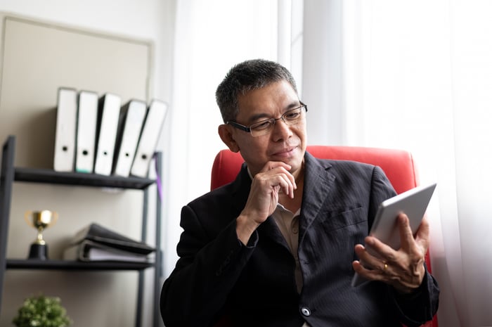 A person in deep thought over a tablet computer.
