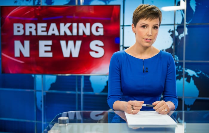 A news anchor with a screen that says Breaking News in the background.