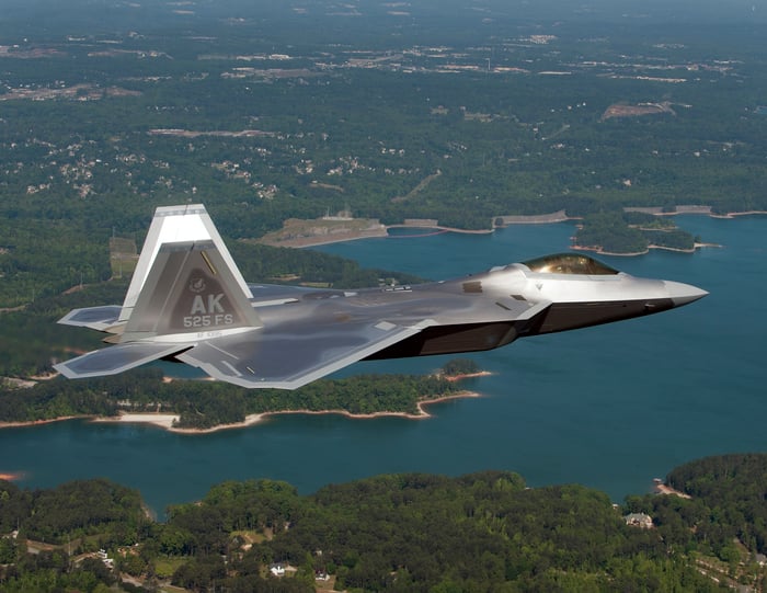 A Lockheed Martin F-22 flying over a lake.