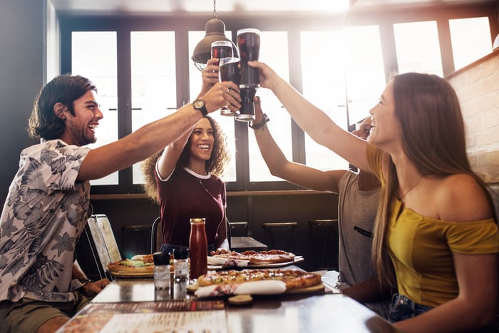 Friends playfully raise glasses of cola at a restaurant.