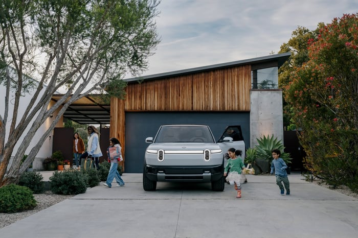 A Rivian R2 SUV parked in a family's driveway.