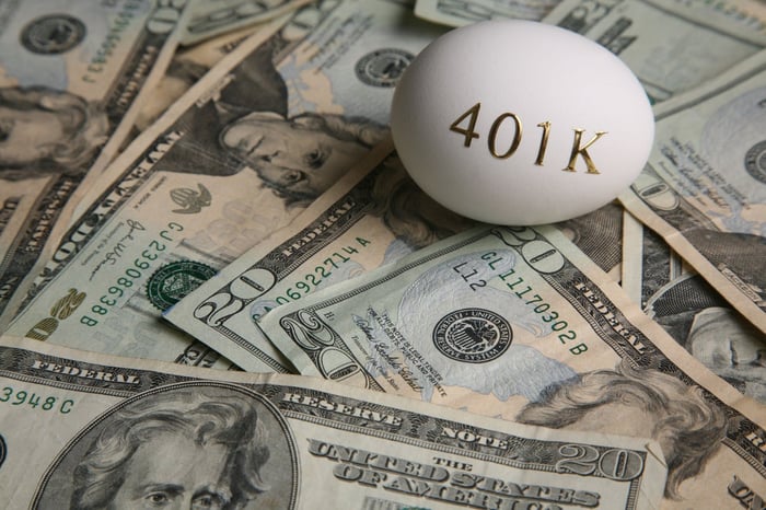 $20 bills spread out with a white egg sitting on top. Gold letters on the egg read "401K."