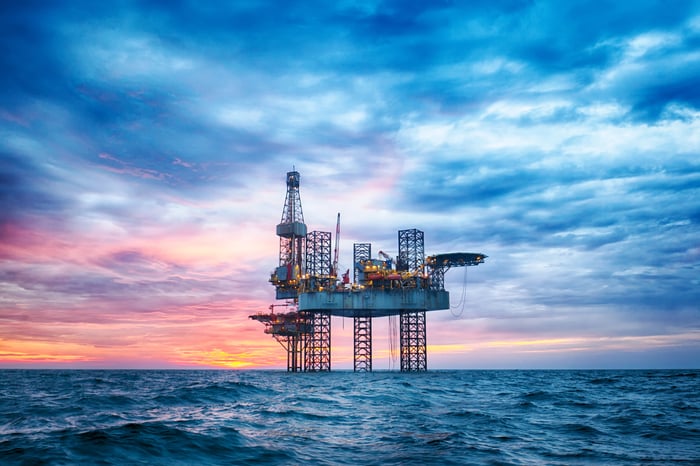 An offshore oil rig in the middle of an ocean. 