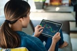 A person looking at a stock chart on a tablet.