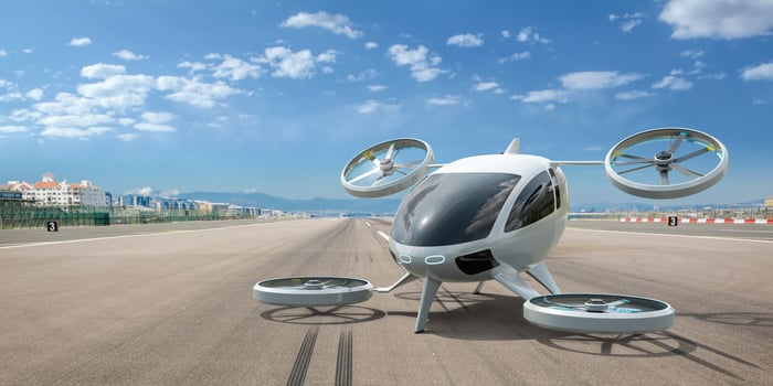 A futuristic looking electric air taxi on a tarmac.