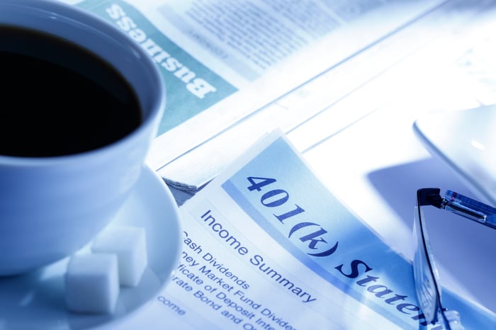 401(k) informational documents with a cup of coffee and pair of glasses sitting on top.