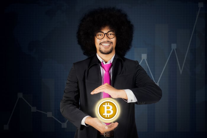 Person in suit, holding a glowing circle with the Bitcoin logo on it.
