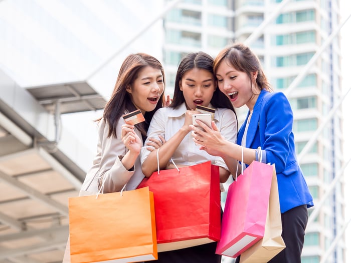 Three people with shopping bags and credit cards.