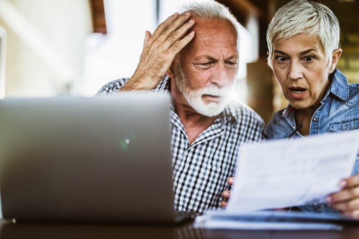 Couple looking at paper with surprised expression.