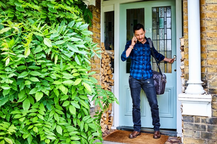 Person talking on the phone leaving their house.