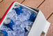 Blue cans of beer in a cooler full of ice.