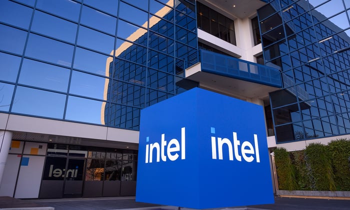 Cube with Intel logo on it outside of a tall glass building.