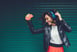 A person smiling and dancing with headphones on while holding a smartphone