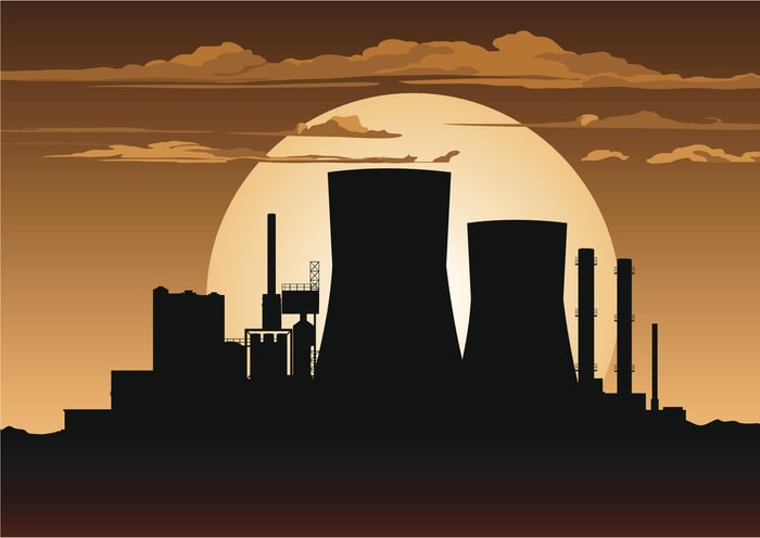 Silhouette of a nuclear power plant against the moon in the background.