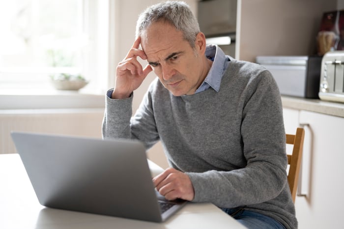 Person looking at laptop, deep in thought.
