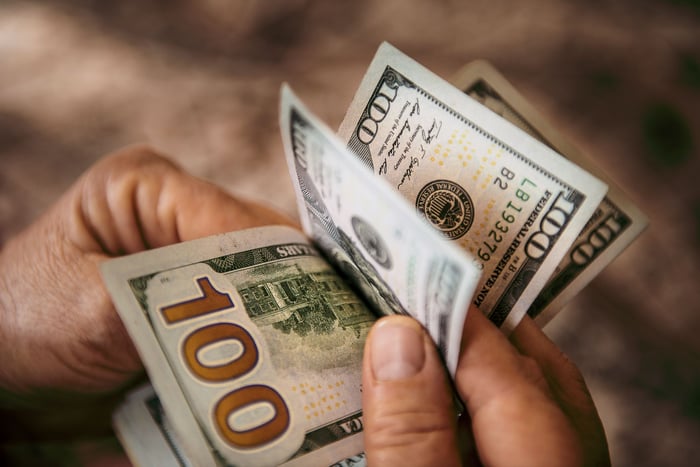 A person flipping through hundred-dollar bills.