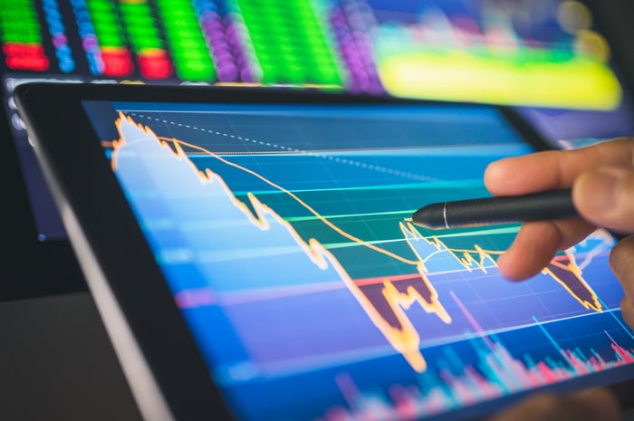 Hand pointing stylus at chart data on tablet.