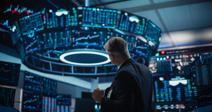 Person looking up at large screens at a stock exchange. 