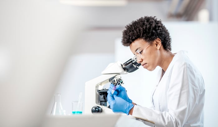 A scientist looking through a microscope.