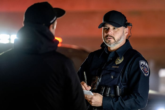 A police officer talking to somebody and taking notes.