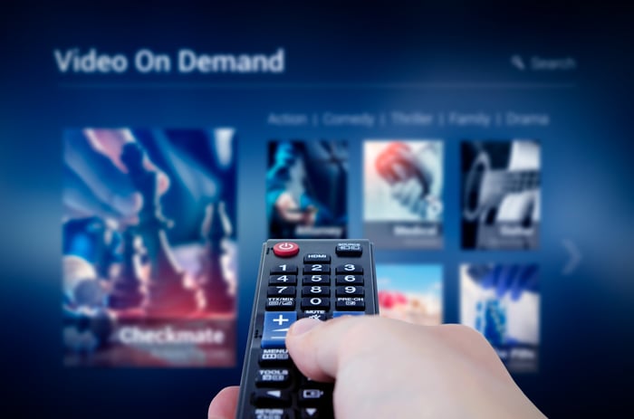 A remote pointing at a TV showing video on demand options.