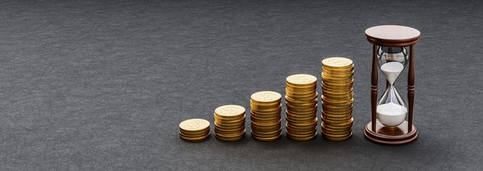 Rising stacks of coins next to an hour glass.