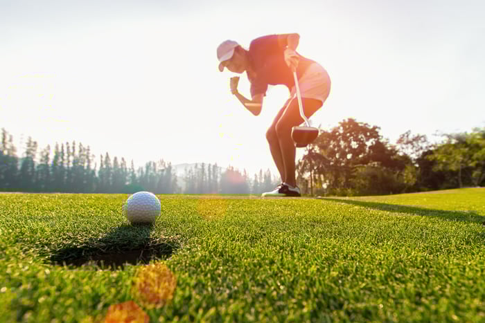 Golfer pumps fist as they make a putt. 