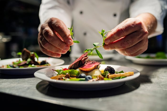 A chef making a salad on a plate.