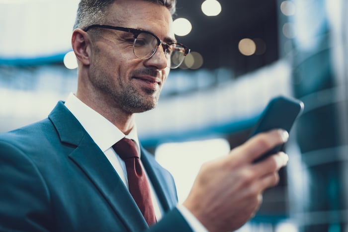 A person smiles while looking at a cellphone.
