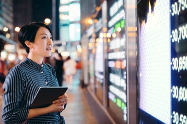 A person looking at the tickers for a stock market exchange.