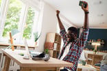 Smiling man with hands in air laptop