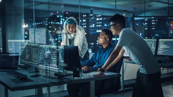 Group of engineers looking at a computer late at night.