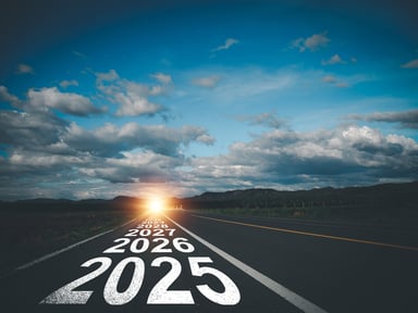 An asphalt road with “2025,” “2026,” “2027,” “2028,” and other years painted on the road heading in the direction of a rising sun.