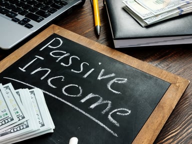 A small chalk board with passive income written out in near stacks of $100 bills.