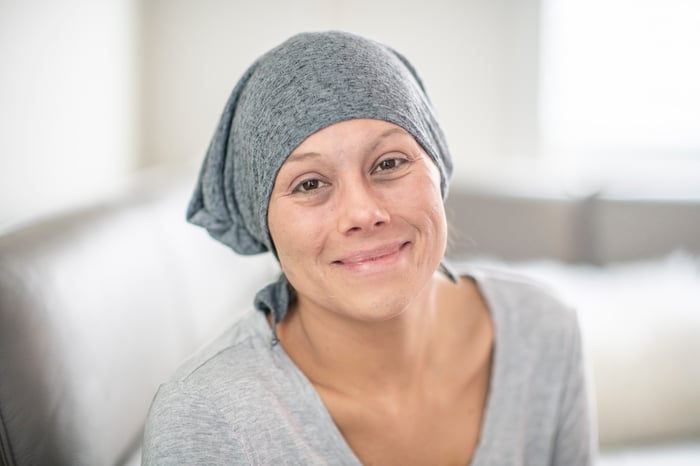 Someone in a grey head covering is smiling at the camera.