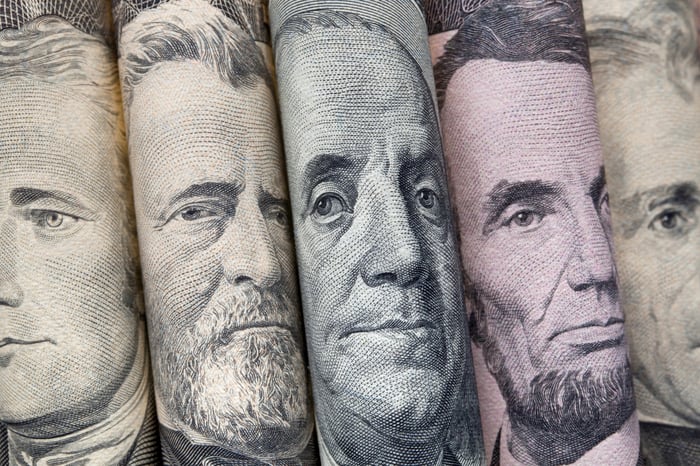 Several cash bills folded to reveal the faces on them.