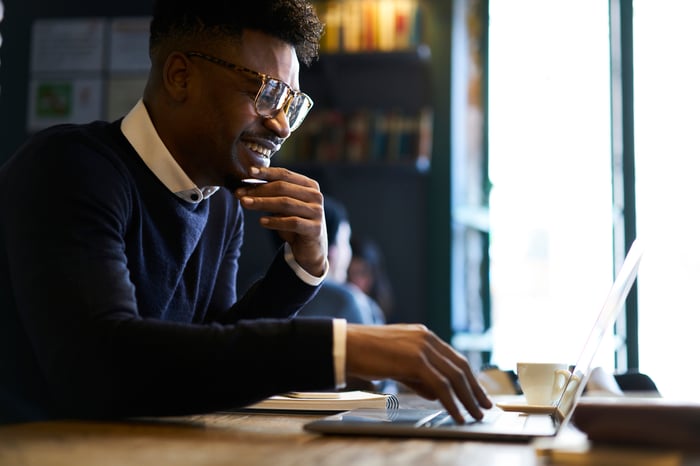 A young person smiles while working on computer.