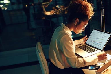 young person sitting at a laptop looking at charts