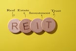 24_06_04 Wooden coins spelling out REIT with words above explaining the acronym _MF Dload -1200x800-5b2df79