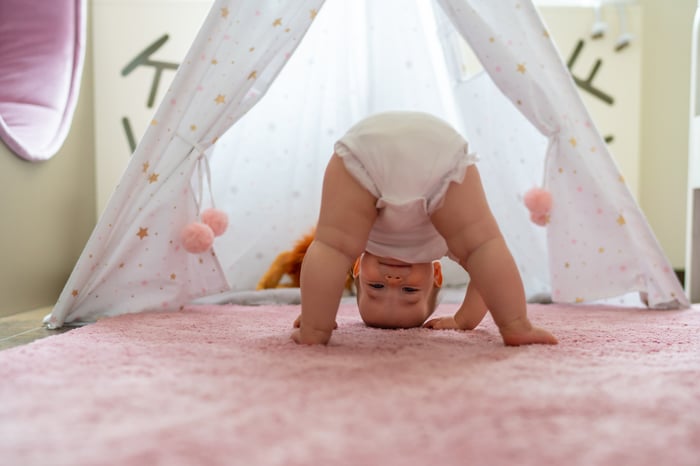 A toddler bending over and playfully looking between their legs.