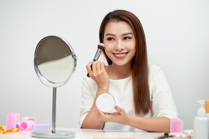 Young woman putting on makeup. 