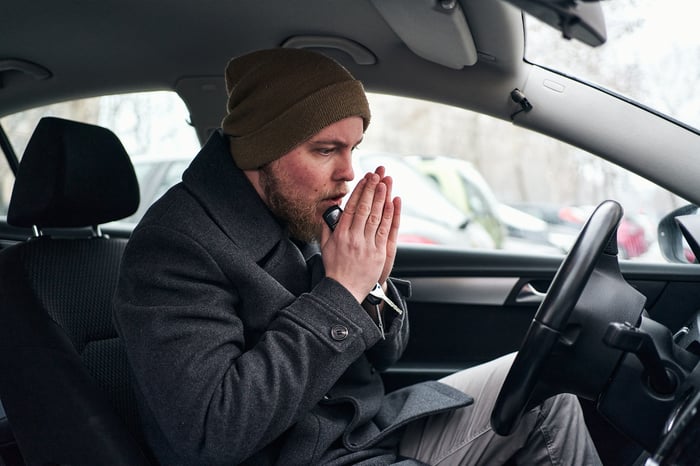 Person putting hands together in the driver's seat of a car.