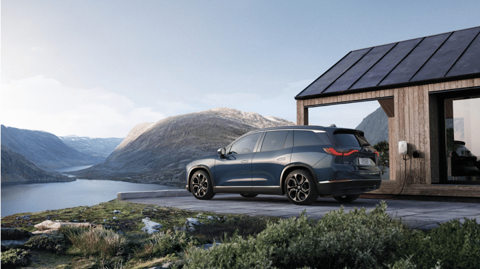 Nio's ES8 SUV parked by a lake house.